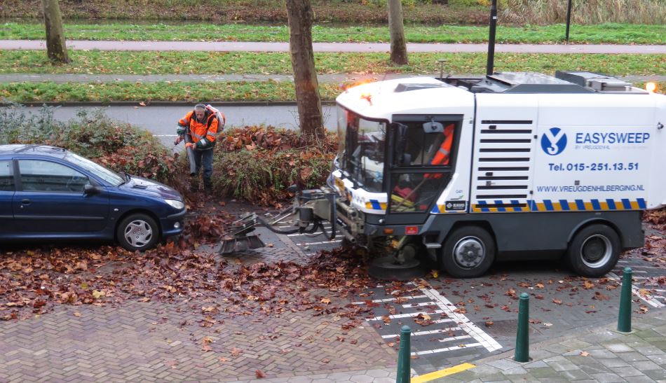 Bladeren ruimen tussen de auto’s