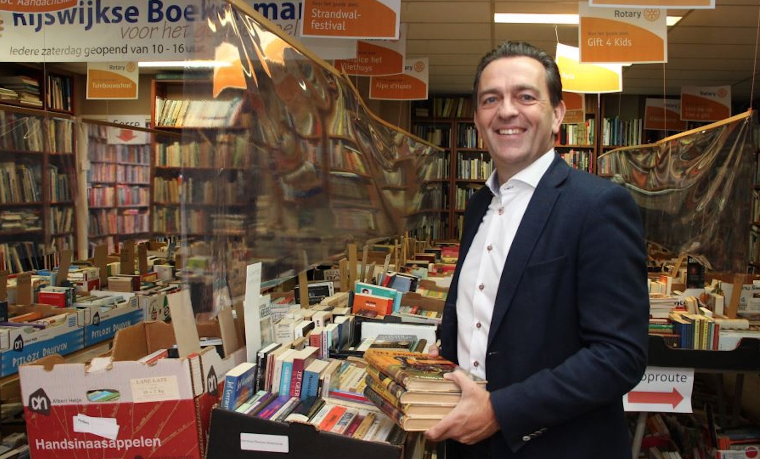 Burgemeester Bezuijen verkoopt boeken voor Strandwalfestival