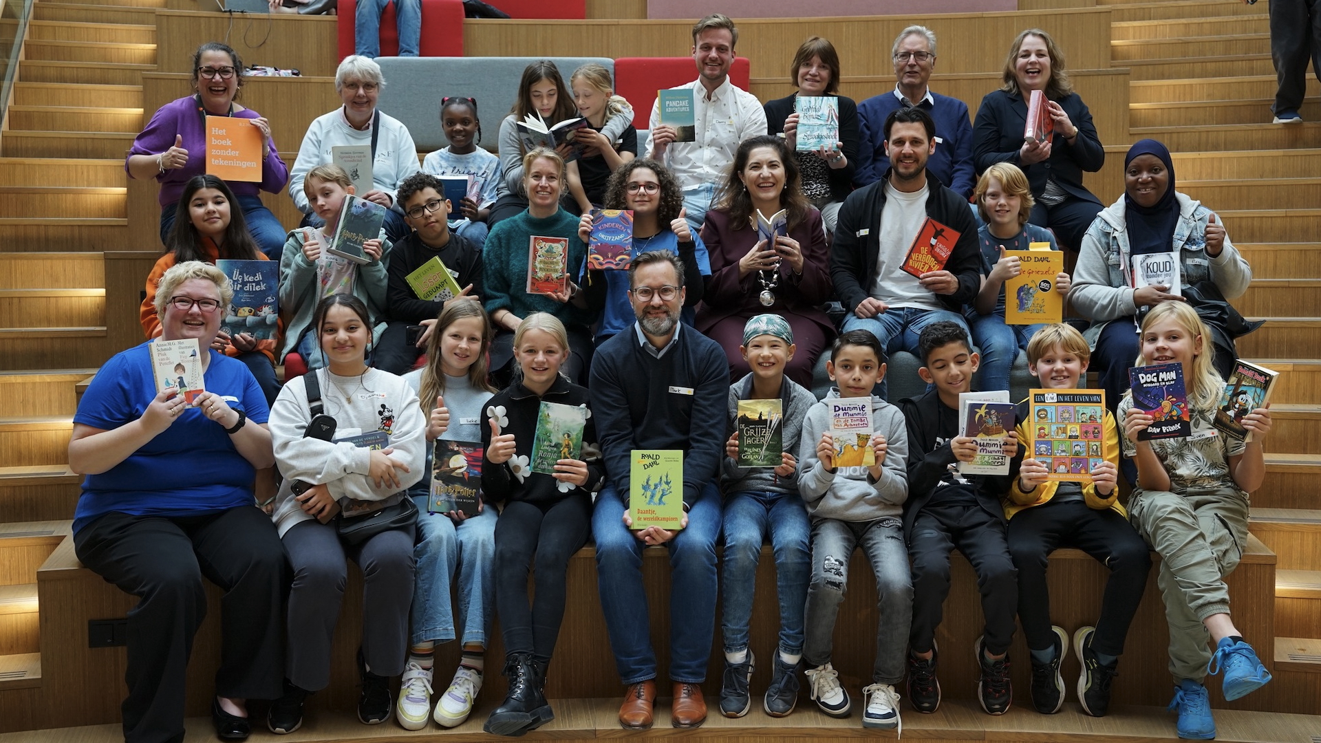 Raadsleden, wethouders en burgemeester lezen boeken met kinderen